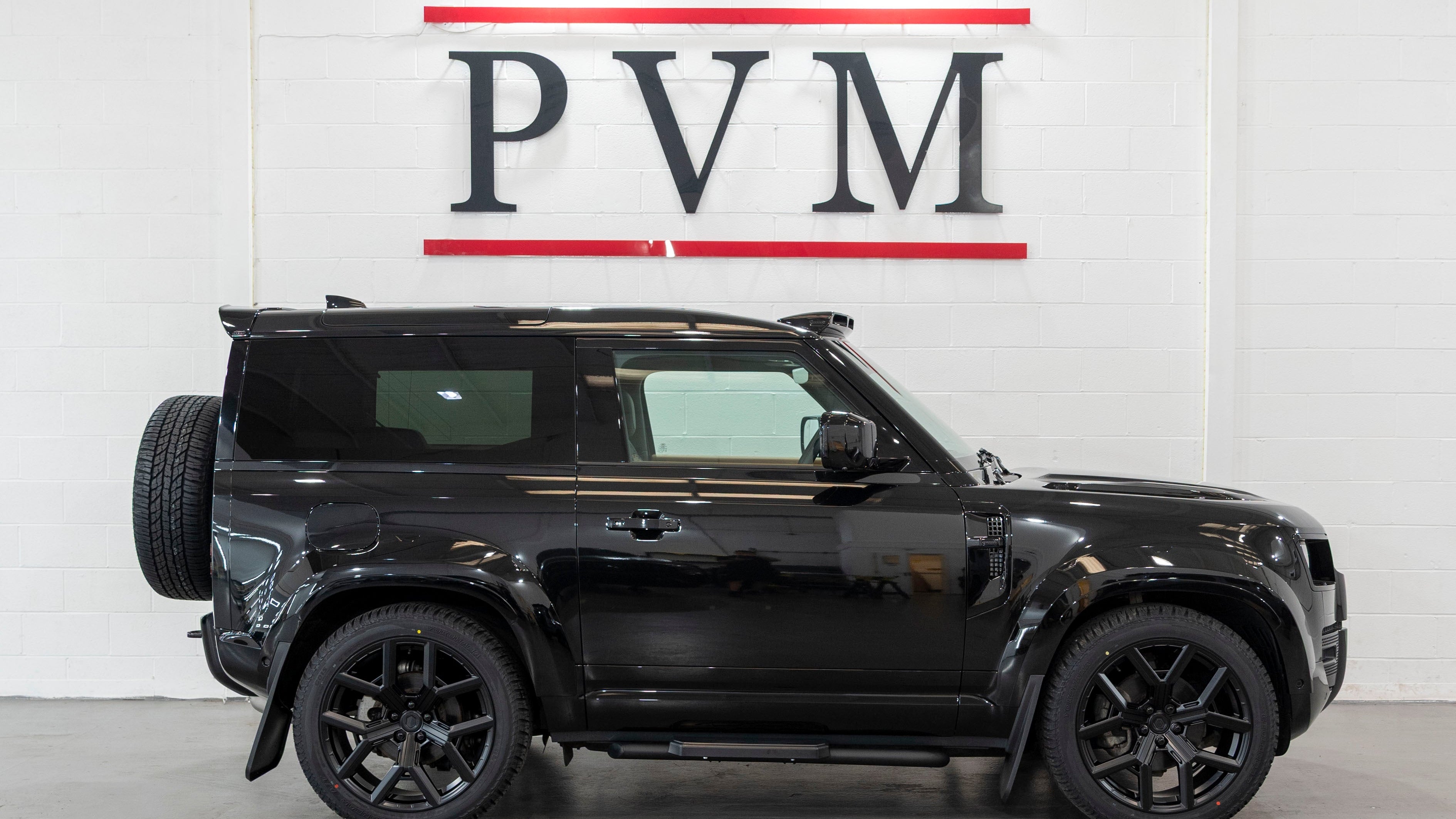 Black SUV parked in a garage with 'PVM' branding on the wall.